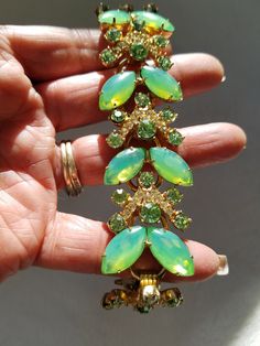 "Featuring this Superb Lime Green Delizza & Elster's AKA \"Juliana\" bracelet from the 1960's. The marquise shaped lime green stones show a glow to them when light shines on them. They resemble a butterfly. Above the two is one round faceted lime green rhinestone, and above that is an upside-down V with pasted clear rhinestones. Some stones are prong set and others are hand pasted. The pattern repeats itself five times. All rhinestones are set in a gold tone setting with a fold over clasp. Back Green Rhinestone Bracelets For Wedding, Vintage Green Bracelets For Party, Green Costume Jewelry Bracelets For Party, Antique Gold Bracelet, Juliana Jewelry, Costume Jewelery, Vintage Rhinestone Jewelry, Green Stones, Metal Bracelet