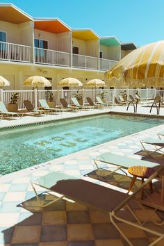 an empty swimming pool surrounded by lawn chairs and umbrellas