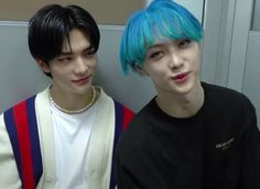 two young men with blue and green hair posing for a photo in front of a mirror