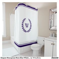 a monogrammed shower curtain in a bathroom with a toilet and sink, along with a mirror