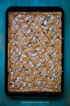 a baking dish with almonds in it on a blue tablecloth and green background