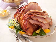 a ham is sitting on a plate with lemons and other food items around it