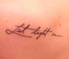 the back of a woman's shoulder with a tattoo that reads let it light in