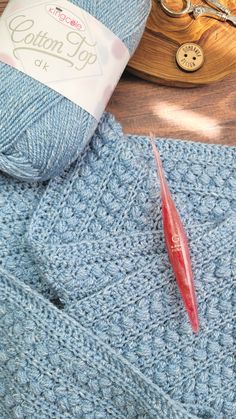 the yarn is blue and has a red crochet hook