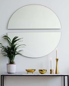 a table with candles and a mirror on it next to a plant in a vase