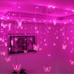 a room with pink lights and butterflies hanging from the ceiling