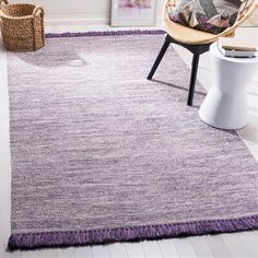 a purple rug with fringes on the floor in a living room next to a chair