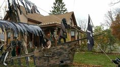 a pirate ship is in front of a house decorated with feathers and other decorations for halloween