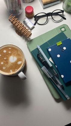 a cup of coffee sitting on top of a table next to a notebook and pen