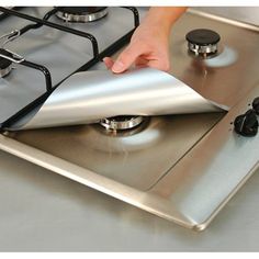 a person is touching the top of a stainless steel stove