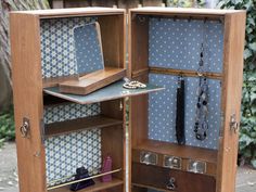 an open wooden box with jewelry in it's door and necklaces hanging from the inside