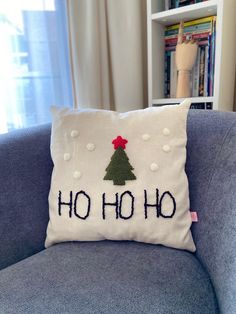 a christmas tree pillow sitting on top of a blue couch next to a book shelf