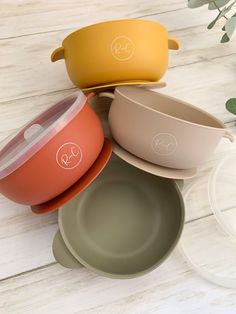 four different colored bowls sitting next to each other on top of a white wooden table