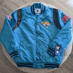 a blue jacket with patches on it sitting on top of a wooden floor next to a white table