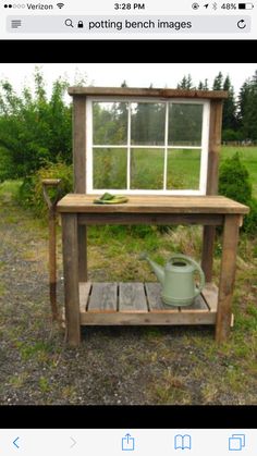 a potting bench with a window and watering can on the ground in front of it