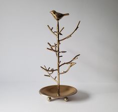 a gold plate with a bird on it and a tree branch in the shape of a bowl