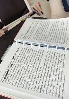 an open book sitting on top of a table next to a pen and laptop computer