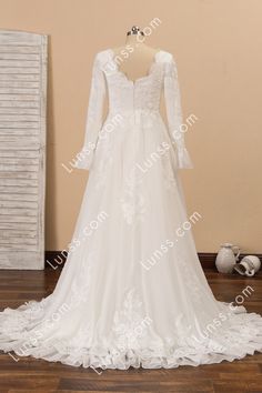 a white wedding dress with long sleeves and laces on the skirt is displayed in front of