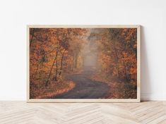 an empty wooden frame on the floor in front of a wall with a photograph of a road