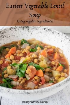 a white bowl filled with vegetables and lentil soup on top of a wooden table