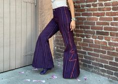 Retro inspired, made to order for the powerhouses of today!  These fit & flare bellbottom pants exude rock star style for miles.  Feast your senses on a stimulating cross between velvet and corduroy, with fabric that features a flat cotton purple base with fuzzy brown variegated stripes, then strut your status right out of the stratosphere, because the tiny accent of zig-zagging electric orange trim will have you sparking attention everywhere. A zipper fly completes this classic look, while two back pockets make it sensible, and double-reinforced seams throughout make it durable enough for stage, play, strolling and rolling! Fabric is limited, so these iconic trousers are made to order for your size. No matter your gender, select your Waist Measurement (or Women's Size); Hip Style/Curvines Purple Lightning Pants, Bellbottom Pants, Electric Orange, Rockstar Style, Violet Brown, Stripe Pants, Hip Style, Brown Velvet, Bell Bottom Pants