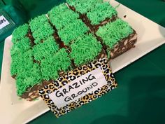 a cake with green frosting sitting on top of a white plate next to a sign