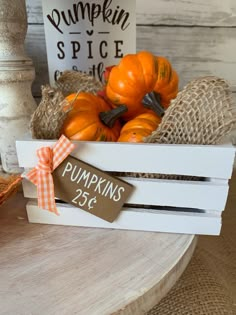 a wooden crate filled with pumpkins sitting on top of a table next to a sign