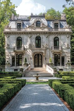 a large white house surrounded by hedges and trees