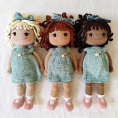 three crocheted dolls sitting next to each other on top of a white sheet