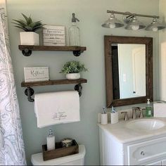 a bathroom with two shelves above the toilet and a mirror over the sink in front of it