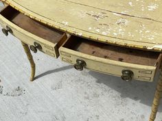 an old wooden table with two drawers on the bottom and one drawer open to show what's inside