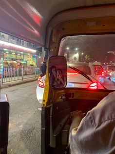 the back end of a truck with cars in it at night time and people walking down the street