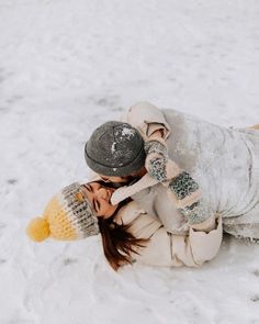 a woman is laying in the snow with her hat on