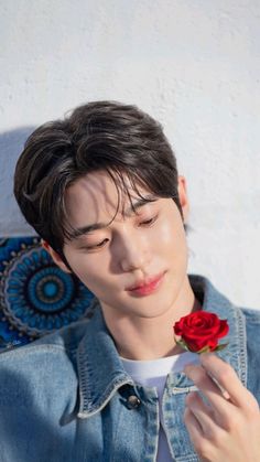 a young man is holding a rose in his hand