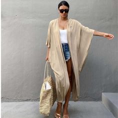 The Sely Kimono & Cover-up is the epitome of effortless elegance and versatility. This flowing garment features a soft, neutral hue that complements any outfit, making it a perfect addition for both casual and sophisticated looks. The lightweight fabric drapes beautifully, providing a flattering silhouette that's both comfortable and stylish.Ideal for layering over a simple tank top and denim shorts, as shown, it enhances the outfit with a touch of sophistication while providing an extra layer o Beige Kimono, Cover Up Kimono, Kimono Women, Tie Dye Swimsuit, Simple Tank Tops, Tunic Dresses, Beach Blouse, Bohemian Tunics, Bathing Suit Dress