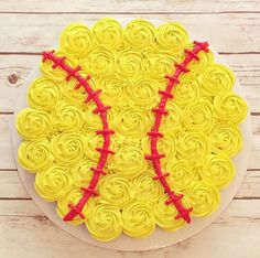 a cake decorated to look like a softball ball with red ribbon on top, sitting on a white plate