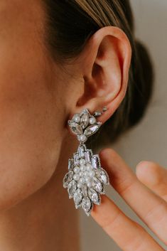 a close up of a person's ear wearing earrings with flowers on them and pearls in the middle