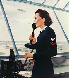 a woman in uniform holding a microphone on top of an airplane deck with planes flying overhead