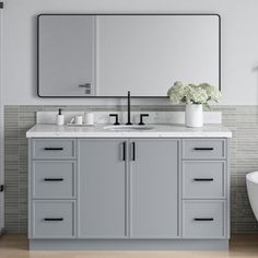 a white bath tub sitting under a large mirror next to a bathroom sink and toilet