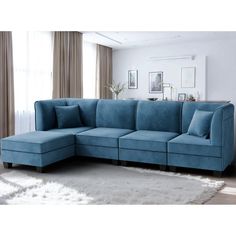 a blue sectional couch in a living room with white rugs and curtains on the windowsill