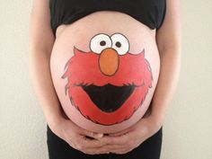 a pregnant woman's belly with an elmo face painted on her stomach and hands