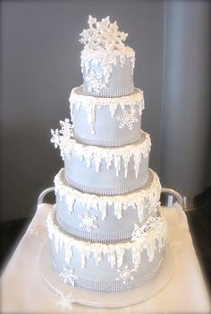 a three tiered wedding cake with white icing on the top and snowflakes on the bottom