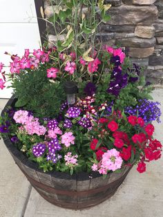 a wooden barrel filled with lots of colorful flowers