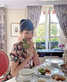 a woman sitting at a table in front of plates and bowls with food on it