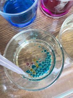 three bowls filled with different colored liquids on top of a wooden table next to each other