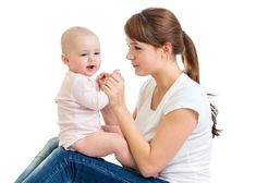 a woman holding a baby while sitting on the floor with it's hands together