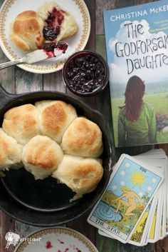 a cast iron skillet filled with cranberry danish pastries next to a book