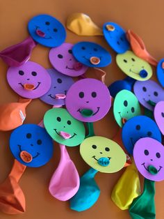 there are many different colored spoons with faces on them and one has a bow tie around his neck