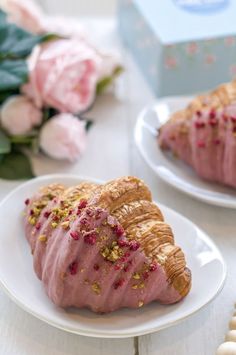 two white plates topped with pastries covered in pink frosting