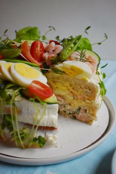 a white plate topped with a piece of cake covered in fruit and veggies